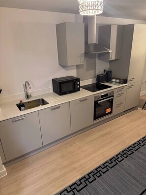 A modern kitchen with a built-in microwave, toaster, and oven. - Apartment in Botanical Gardens, Old Trafford (Manchester)