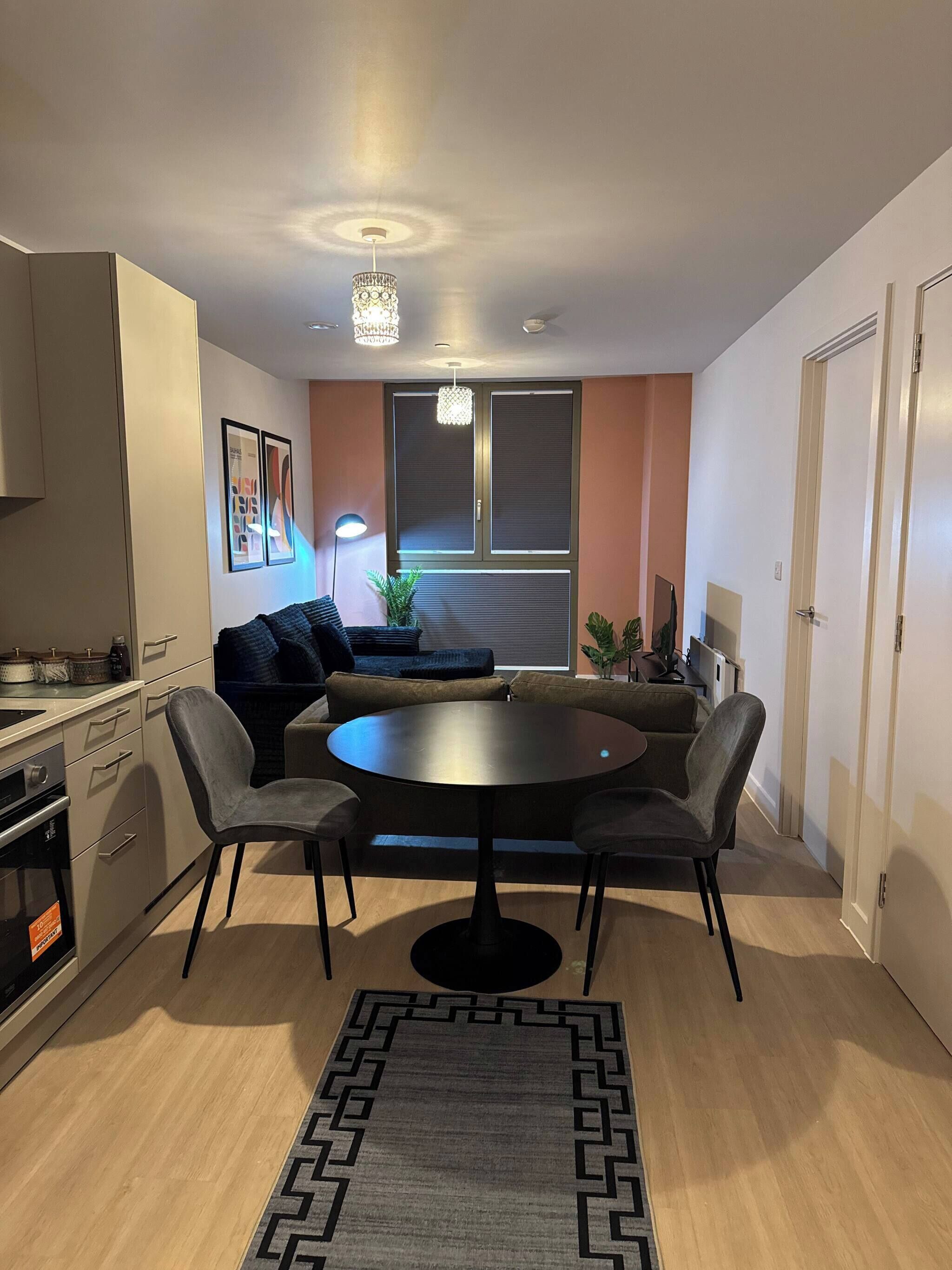 Een compacte leefruimte met een kitchenette, een ronde eettafel en een bank.