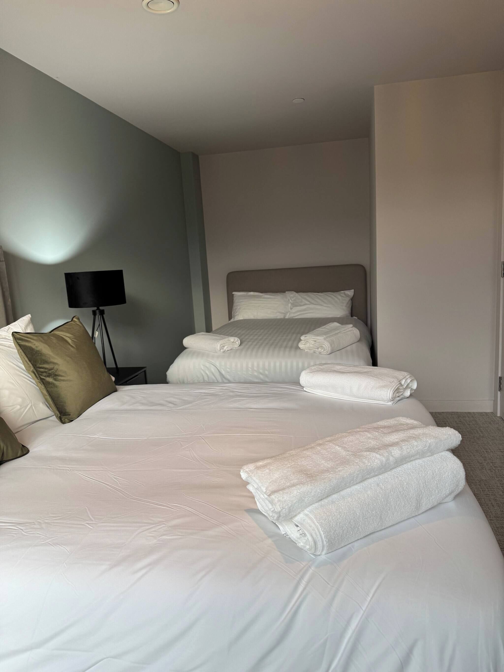 Ein Hotelzimmer mit einem großen Bett, einer Nachttischlampe und ordentlich gefalteten Handtüchern.