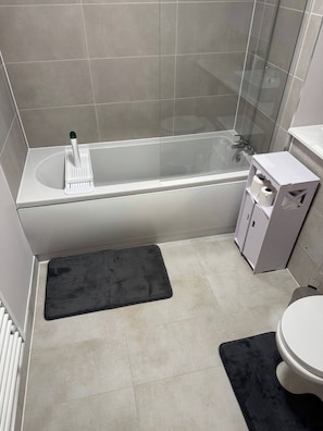 A bathroom with a bathtub, a toilet, and a shower area. - Apartment in Botanical Gardens, Old Trafford (Manchester)