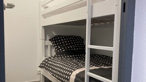 Uma cama de solteiro com um edredom xadrez e um travesseiro com padrão semelhante.