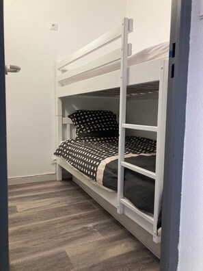 Ein Etagenbett mit karierter Bettdecke und einem Kopfkissen in ähnlichem Muster.