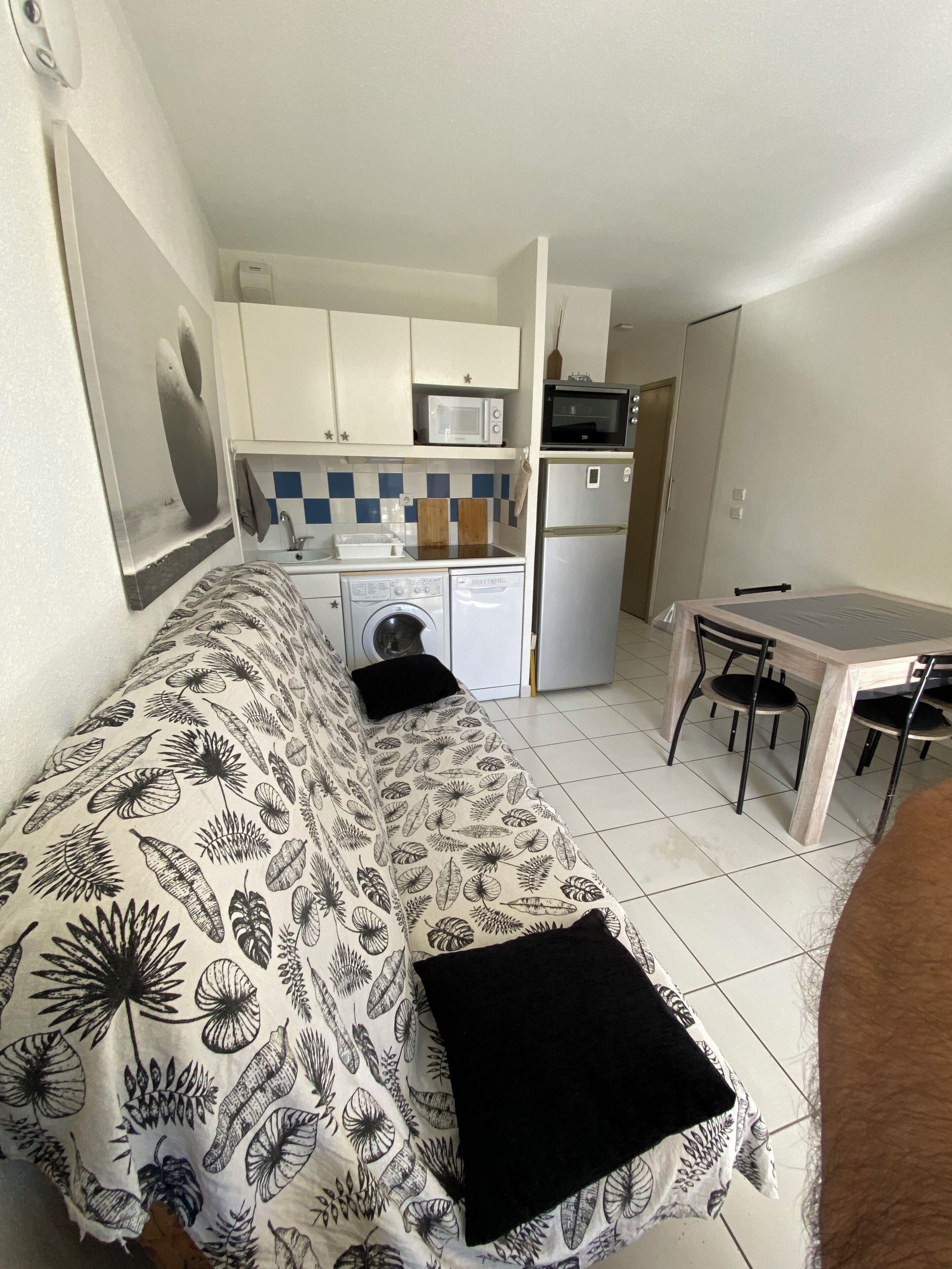 Um espaço compacto com cozinha compacta, área de refeições e sofá com estampa de folhas.