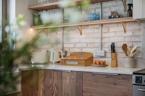 A kitchen with wooden cabinets, a countertop, a coffee maker, a box labeled 'CITELERY,' and a knife block. - The Fold | A Tucked-Away 2 Bedroom Retreat In Buckinghamshire (Milton Keynes)