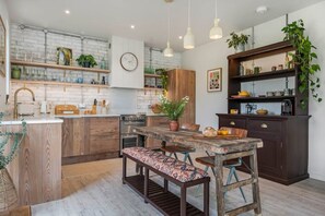 Una cocina moderna con armarios de madera, horno empotrado y una zona de comedor con un banco.