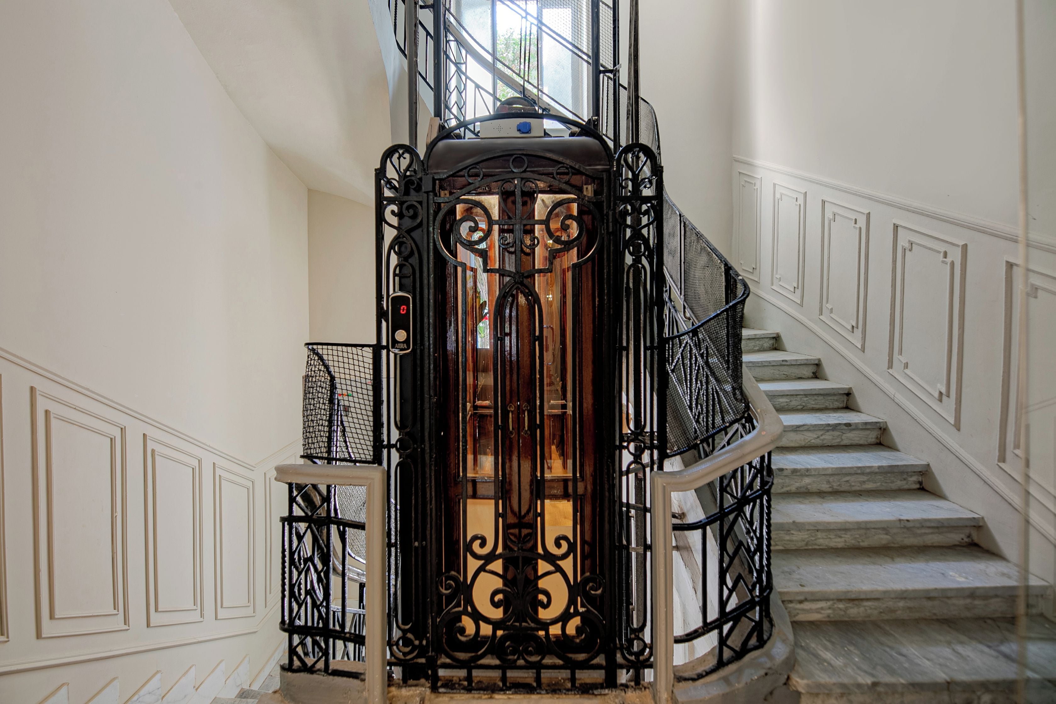 Una escalera con barandilla de hierro forjado y una puerta de vidrio en la parte superior.