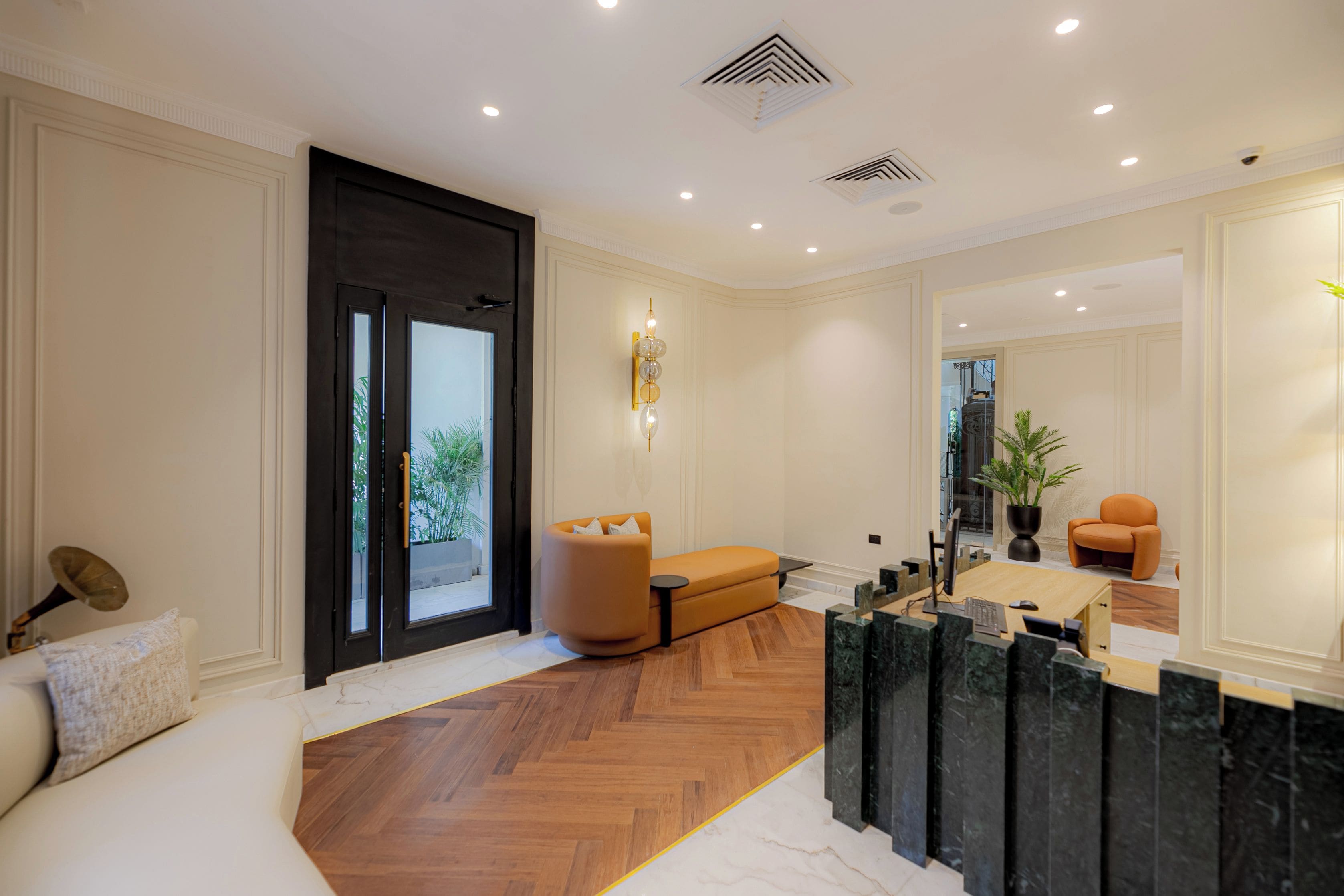 Un intérieur moderne avec un plancher en bois, un canapé, un bureau avec un ordinateur et un grand miroir.