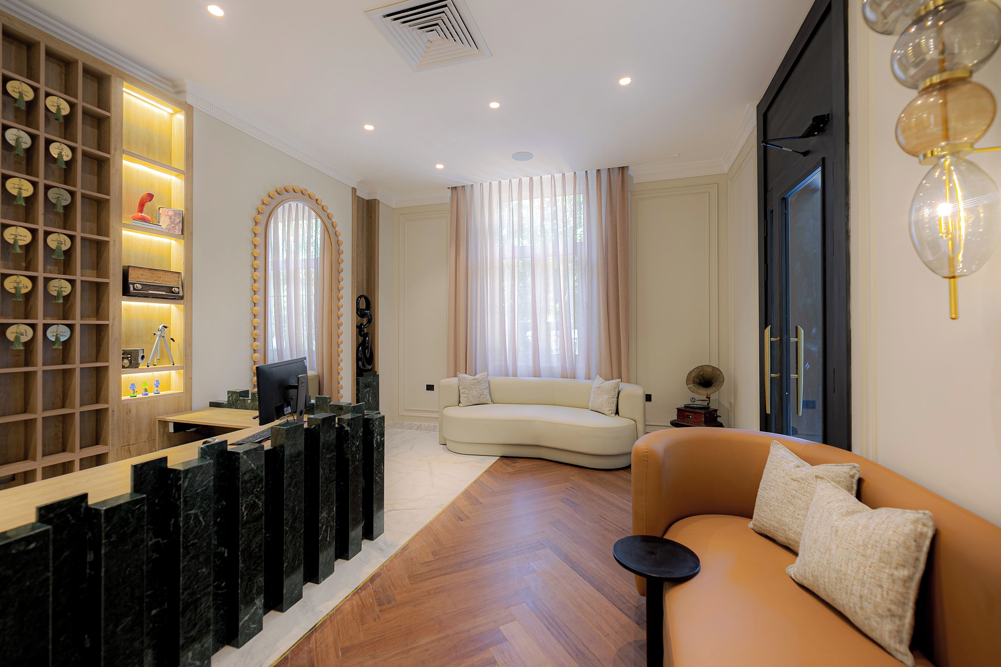 Una sala de estar moderna con un escritorio de madera, un sofá y un amplio ventanal con cortinas.
