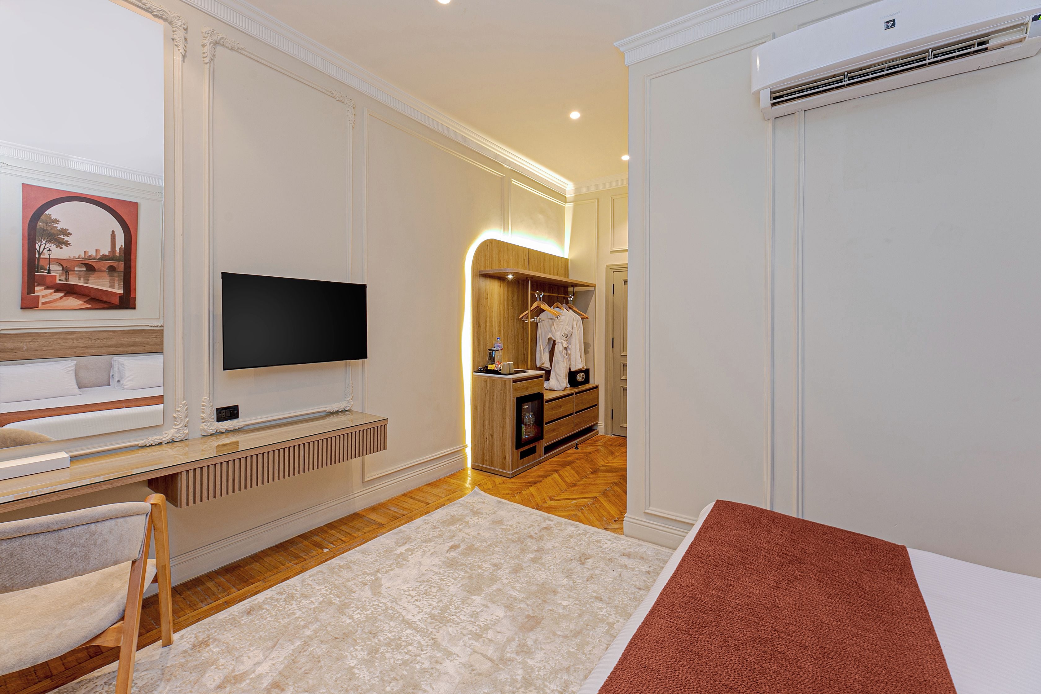 Een hotelkamer met televisie, een bed, bureau, stoel, kledingkast en een badkamer.