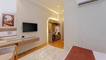 Een hotelkamer met televisie, een bed, bureau, stoel, kledingkast en een badkamer.