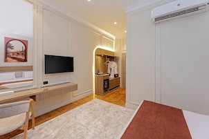 A hotel room with a television, a bed, a desk, a chair, a wardrobe, and a bathroom.
