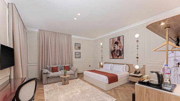 Una habitación de hotel con cama, sofá, escritorio, televisor y baño.