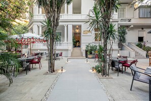 A courtyard with outdoor seating, palm trees, and a building entrance.