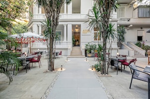 Un patio con mobiliario exterior, palmeras y la entrada a un edificio.