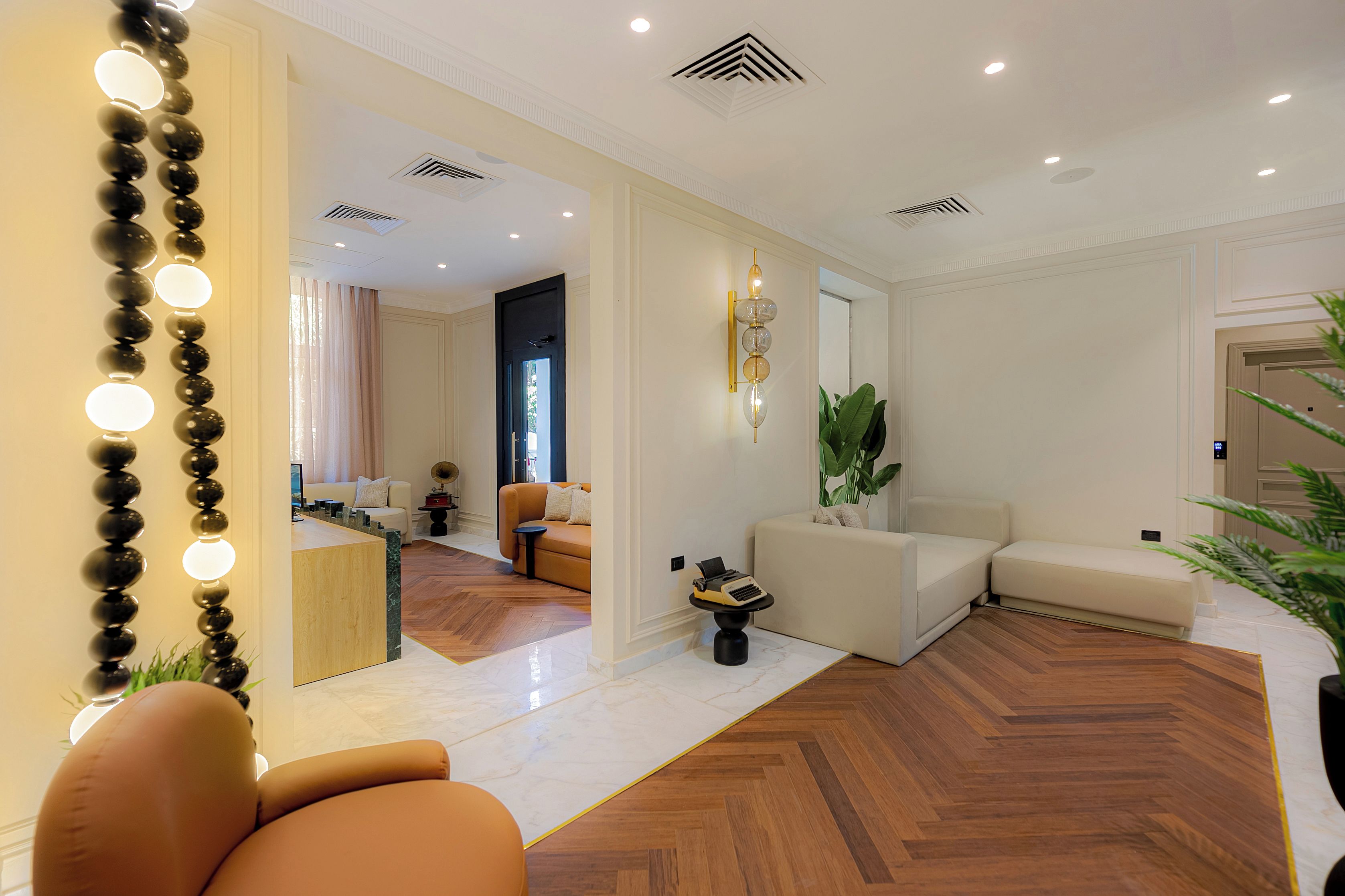 Una sala de estar moderna con piso de madera, un sofá, una mesa de centro y un espejo decorativo.
