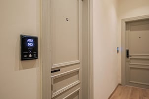 A hallway with a digital door lock displaying 'AJIRA 303' and options for 'Clean Room' and 'Laundry.'