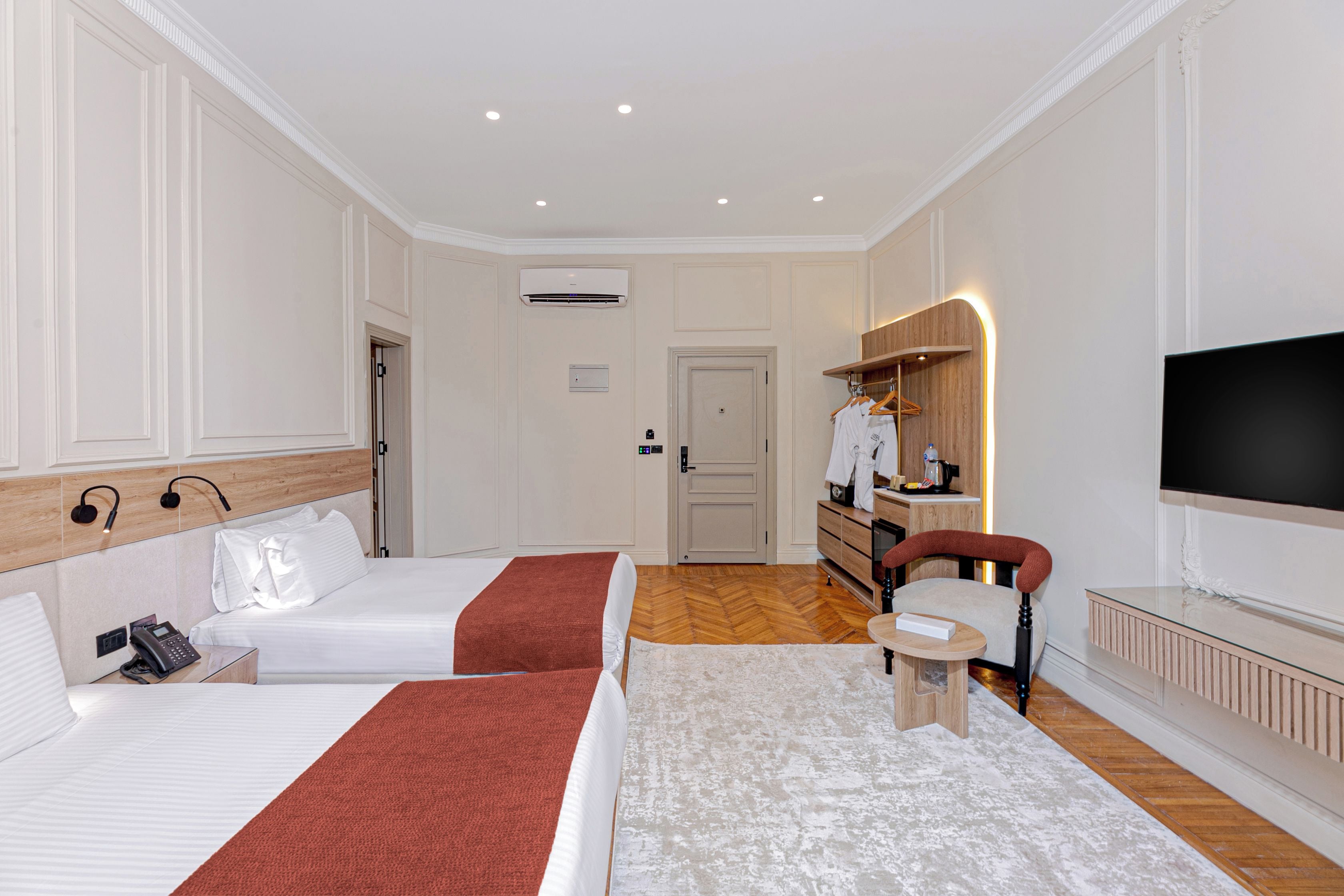 Habitación de hotel con dos camas, un escritorio, una silla, un televisor y un armario.