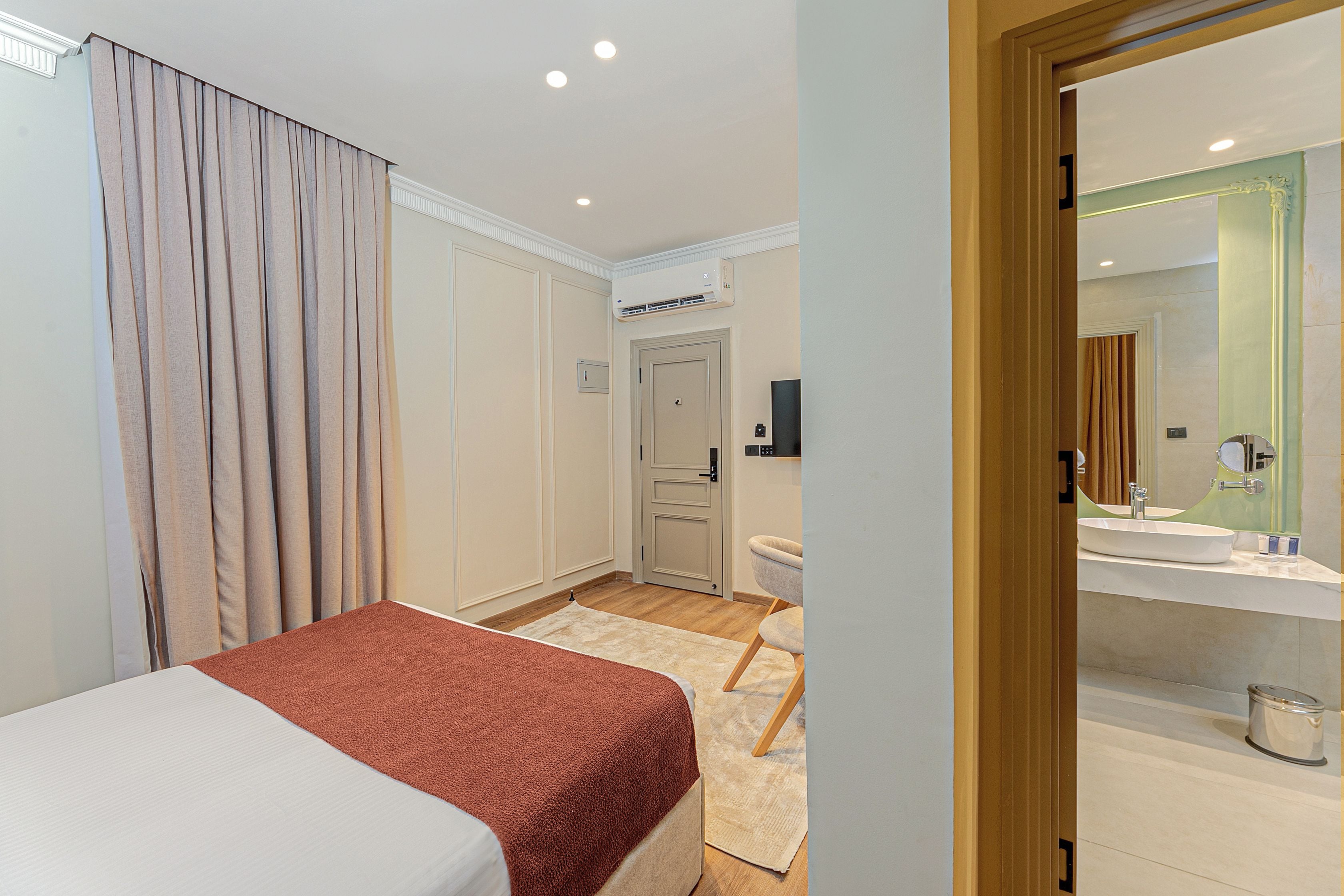 Una habitación de hotel con una cama, un baño con espejo y una puerta que da a otra habitación.