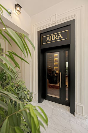 A black-framed entrance with the name 'AJIRA' in gold lettering. - AJIRA Zamalek Hotel (Cairo)
