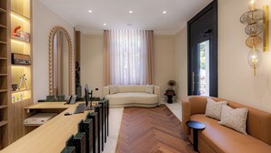 Una sala de estar moderna con piso de madera, un sofá beige, un escritorio de madera con una computadora y un espejo grande con luces.
