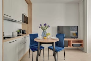 Eine moderne Küche mit Essbereich, inklusive Tisch mit Stühlen, Fernseher und Blumen in einer Vase.