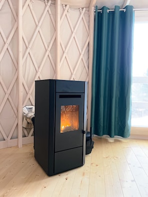 A black wood-burning stove in a room with wooden flooring and a lattice wall. - Restart Kashubia - Yurt in a Landscape Park (Dejk)