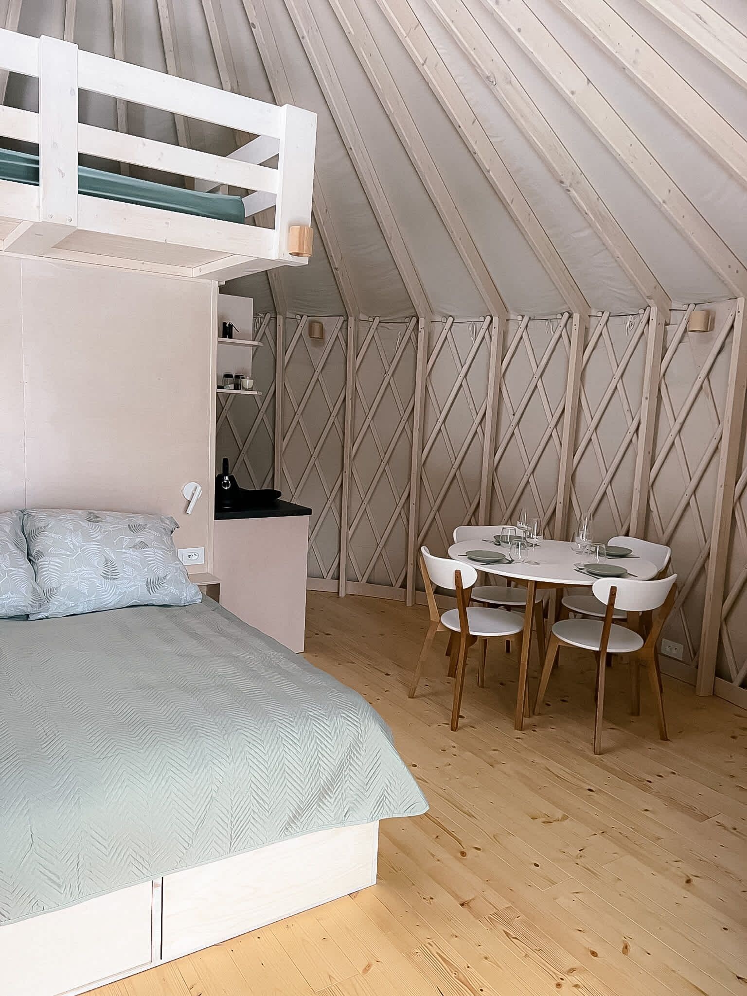 A tent with a bunk bed, a small table with chairs, and a kitchenette area.