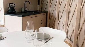 Un'area pranzo con un tavolo apparecchiato per due, una cucina sullo sfondo e un muro decorato.