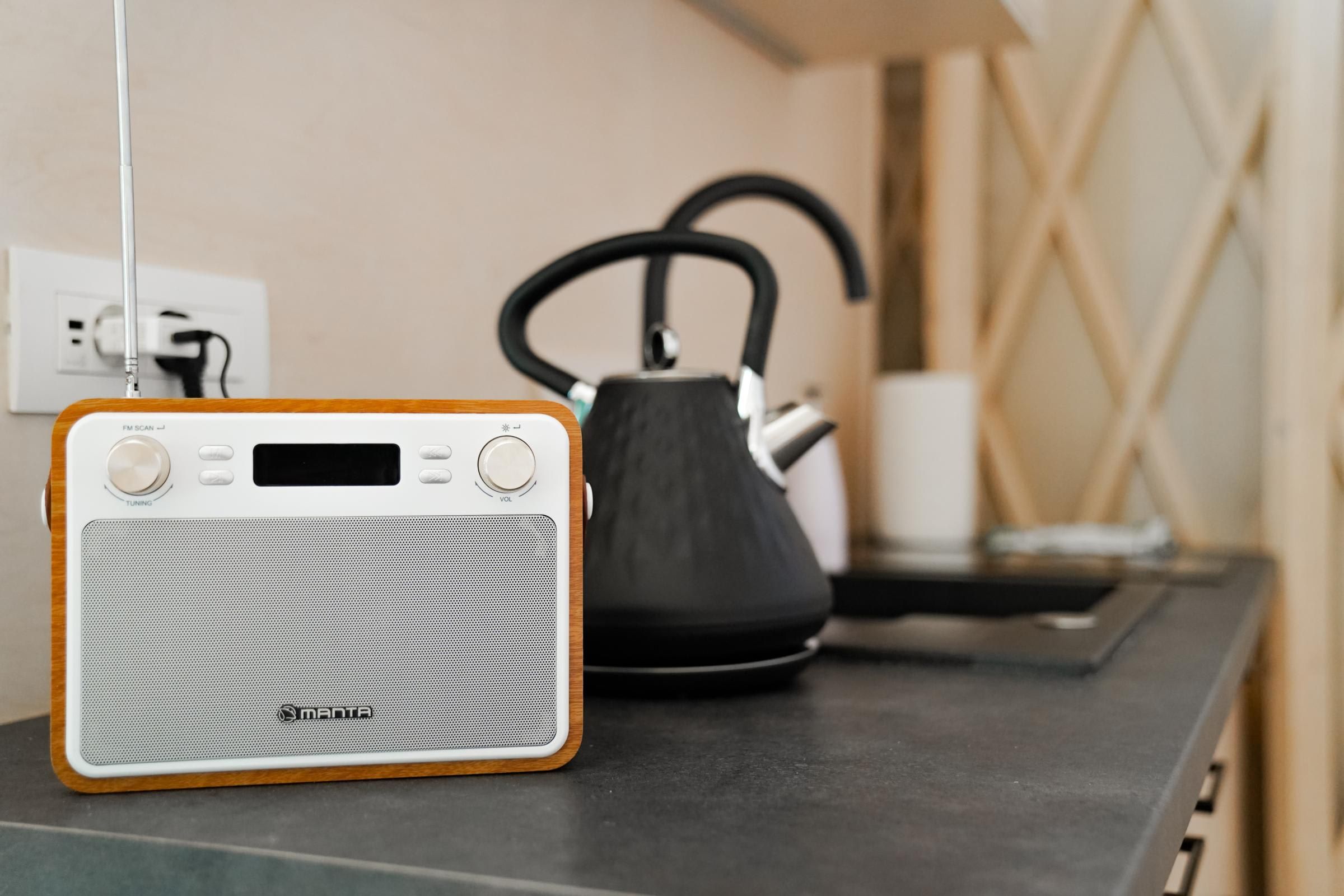 A radio with a wooden frame and a kettle on a table.