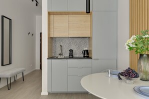 A modern kitchen with grey cabinets, a black and white backsplash, and a round dining table with a vase of flowers. - Śląska 5 | Gym | Perfect for Couples (Gdańsk)
