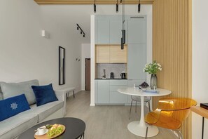A modern living room with a sofa, coffee table, and a dining area with a table and chairs. - Śląska 5 | Gym | Perfect for Couples (Gdańsk)