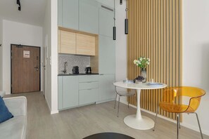 A modern kitchen with light wood cabinets, a black and white backsplash, and a round dining table with two chairs. - Śląska 5 | Gym | Perfect for Couples (Gdańsk)