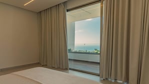 A hotel room with a large bed, a sliding glass door leading to a balcony with a view of the sea. - Villa Rose (Las Terrenas)