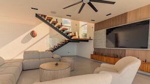 A modern living room with a sofa, coffee table, and a TV mounted on the wall. - Villa Rose (Las Terrenas)