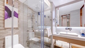 Een moderne badkamer met een glazen douchecabine, een grote spiegel en een wit wastafelmeubel.