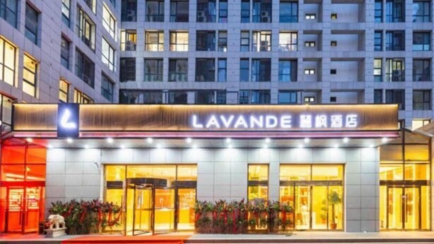 Een hotel met een opvallend bord, grote ramen en een goed verlichte ingang.