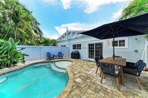 A backyard with a swimming pool, patio furniture, and a covered table. - The Blue Haven: Ground level 2 BR with private pool! (Holmes Beach)