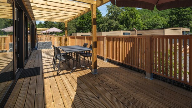 Ett trädäck med en pergola, utomhusmöbler och utsikt över ett bostadsområde.