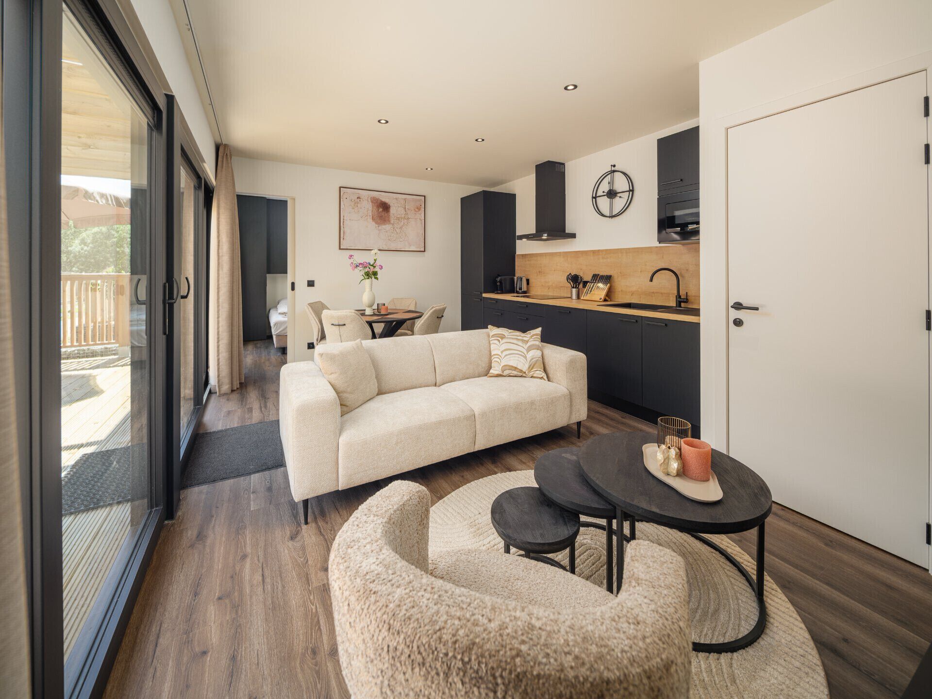 Een moderne woonkamer met een bank, een salontafel en een eethoek met een kleine tafel en stoelen.