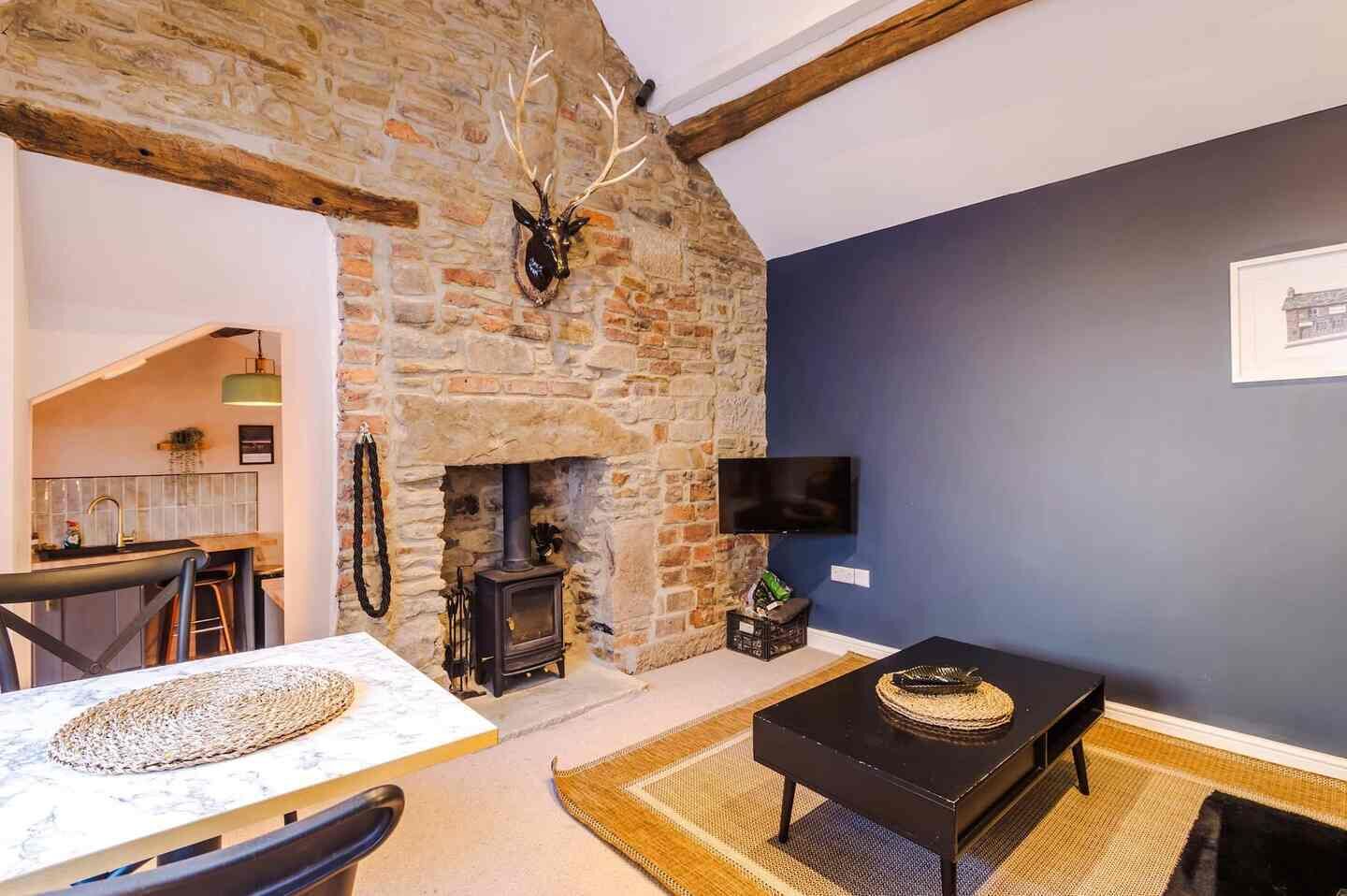 A room with a stone wall, a fireplace, a television, and a dining area with a table and chairs.