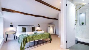 A bedroom with a bed, bedside tables, a mirror, a nightstand, and a bathroom with a shower. - The Vault - Boutique Cosy Peak District Retreat in a Grade II listed building (Chapel-en-le-Frith)