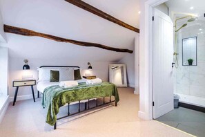 A bedroom with a bed, bedside tables, a mirror, a nightstand, and a bathroom with a shower. - The Vault - Boutique Cosy Peak District Retreat in a Grade II listed building (Chapel-en-le-Frith)
