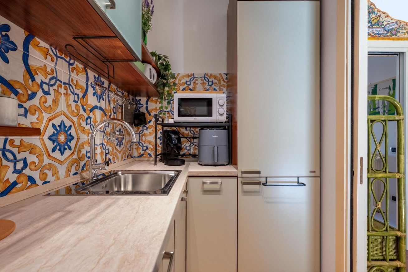 Cocina compacta con microondas, cafetera y lavabo.