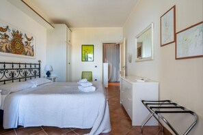 Ein Hotelzimmer mit Bett, Schminktisch, Spiegel und Bildern an den Wänden.