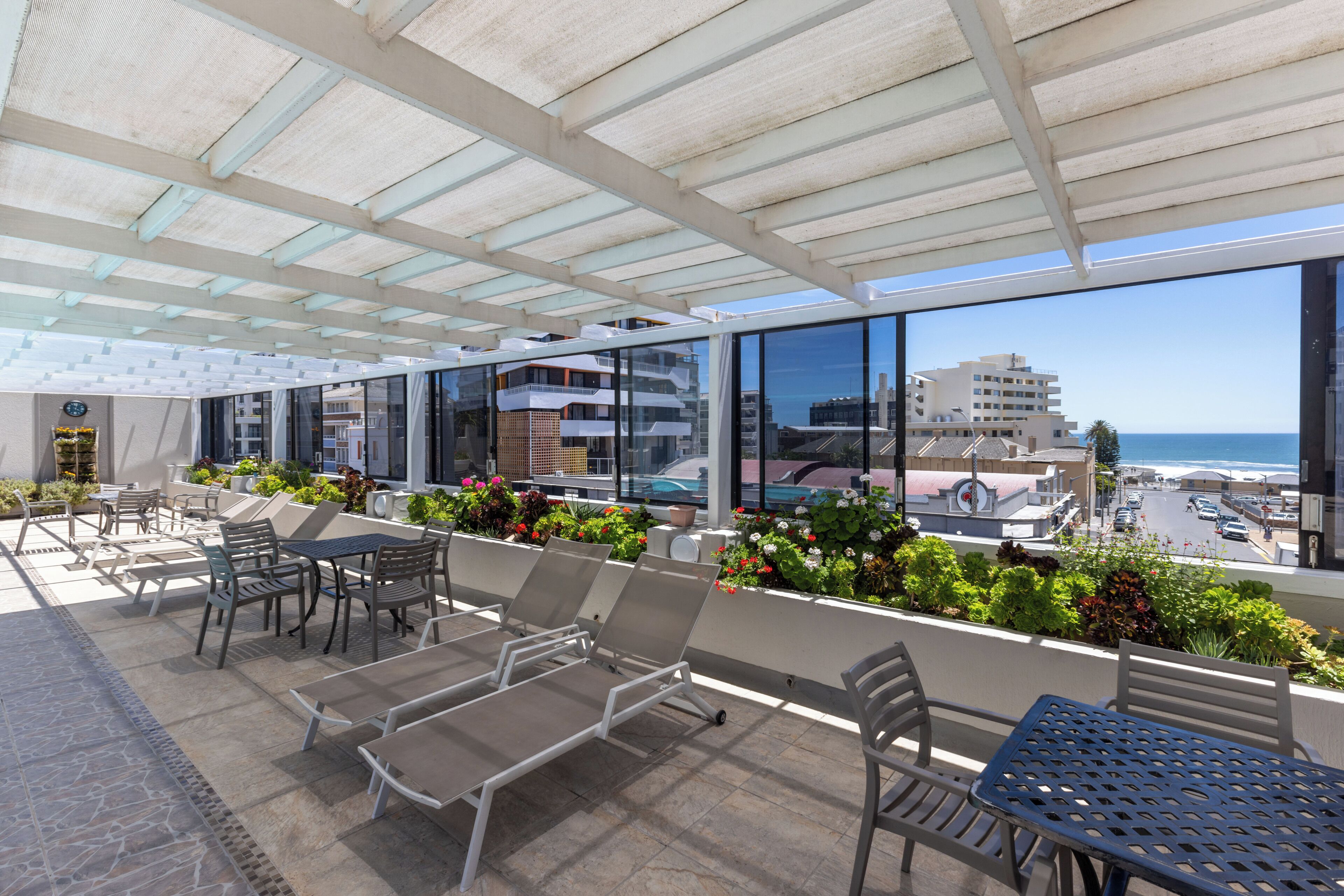 A rooftop terrace with outdoor seating, a pool, and a view of the ocean and buildings.