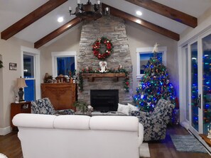 A living room with a stone fireplace, a Christmas tree, and a white sofa.