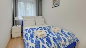 Ein Hotelzimmer mit einem Bett, einem Nachttisch, einer Lampe und einem gerahmten Bild an der Wand.