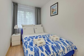 Ein Hotelzimmer mit einem Bett, einem Nachttisch, einer Lampe und einem gerahmten Bild an der Wand.