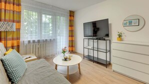Ein stilvolles Wohnzimmer mit einer Couch, einem Couchtisch, einem Fernseher und einer kleinen Pflanze.