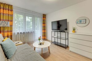 Ein stilvolles Wohnzimmer mit einer Couch, einem Couchtisch, einem Fernseher und einer kleinen Pflanze.